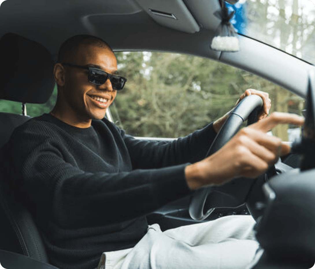 A smiling man driving a car